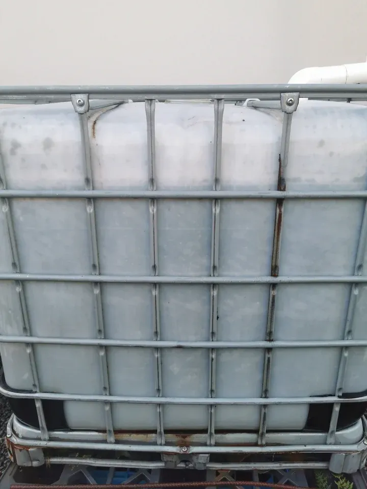 After: the same IBC tank with green streaking largely removed from the plastic face.